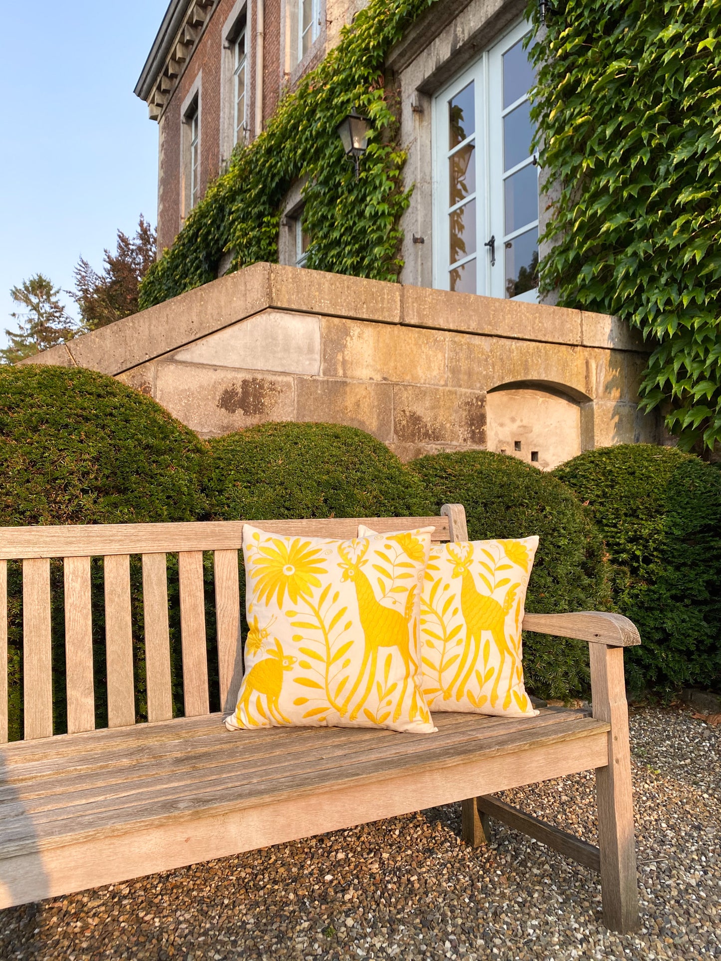 Vibrant Tenango Otomi Embroidery Cushion with Animal and Flower Designs, gracing a garden bench