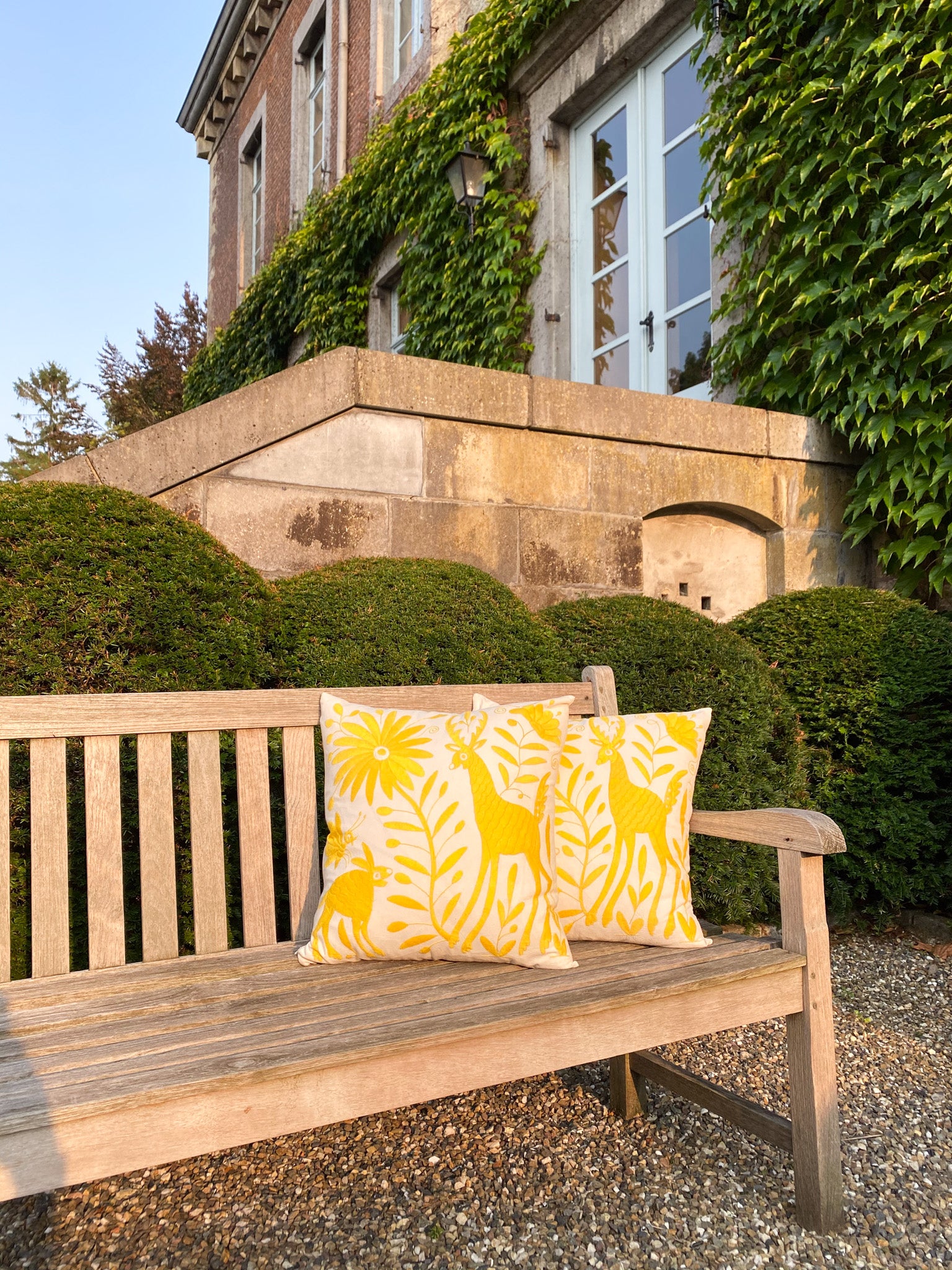 Vibrant Tenango Otomi Embroidery Cushion with Animal and Flower Designs, gracing a garden bench