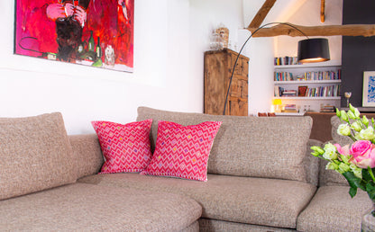 Vibrant red cushion, diamond brocade pattern with vibrant hues, elevating living room decor.