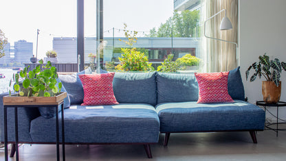 Vibrant red cushion, diamond brocade pattern with vibrant hues, elevating living room decor.