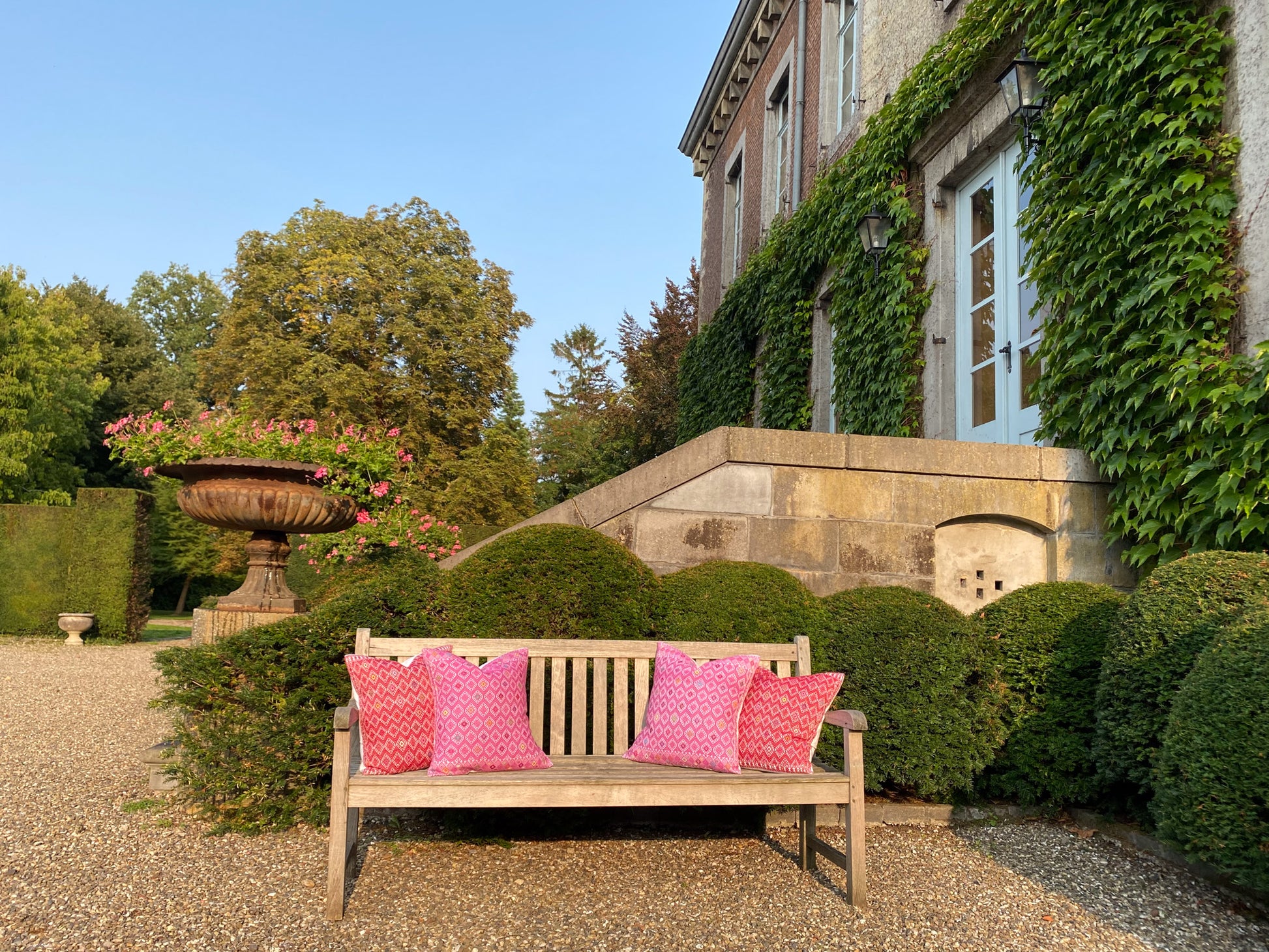 Vibrant Maria Red and Pink Cushions Designs, gracing a garden bench.