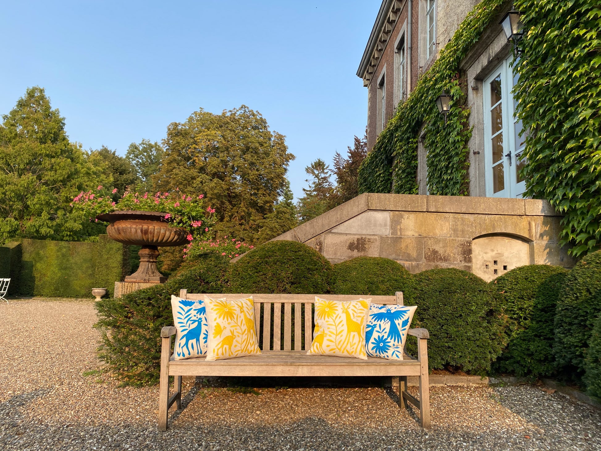 Vibrant Tenango Otomi Embroidery Cushion with Animal and Flower Designs, gracing a garden bench.